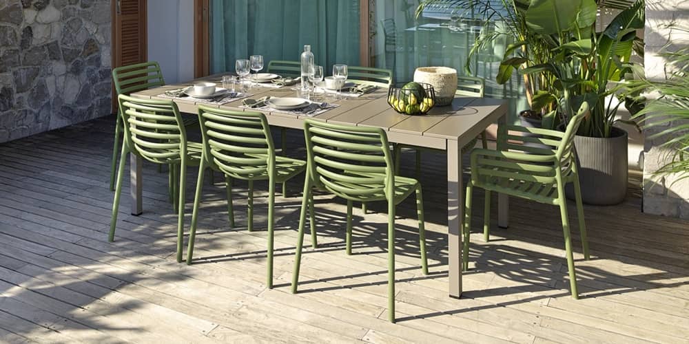 Auf einer grossen Terrasse steht ein gedeckter Outdoortisch und acht Outdoor St&uuml;hle